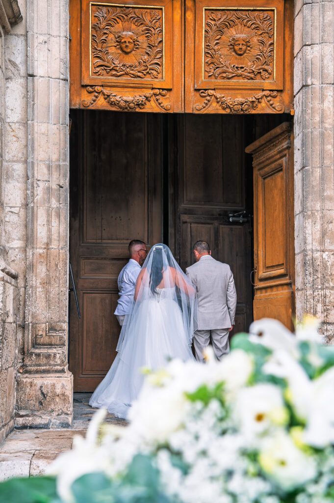 Mariée en robe et voile au bras de son accompagnant à l'entrée de la cathédrale